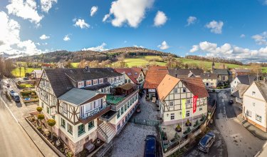 Blick auf Fachwerkhäuser in einem Dorf mit Hügeln und blauem Himmel im Hintergrund