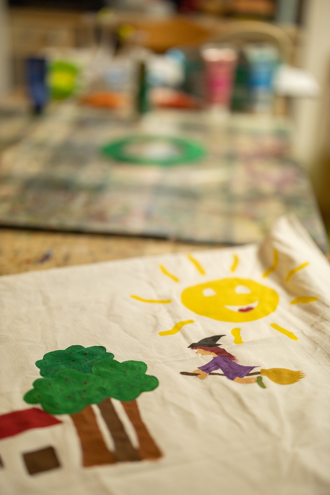 Nahaufnahme einer bemalten Stofftasche mit Sonne, Hexe auf Besen und Bäumen auf einem Tisch