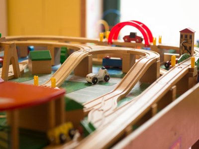 Holzeisenbahn mit Brücke, Spielzeugautos und Häusern auf einem Spieltisch