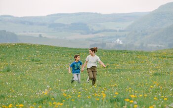 Kinder laufen in der Blumenwiese