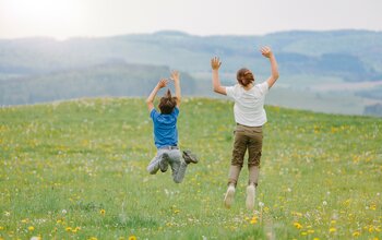 Kinder springen auf der Blumenwiese in die Höhe