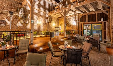 Gemütlicher Innenbereich mit Holzbalken, Backsteinwänden und Sitzgruppen mit Tischen und Stühlen