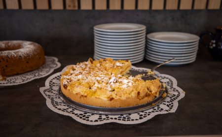 Kuchen mit Streuseln auf einer Serviette vor gestapelten Tellern auf einer Theke