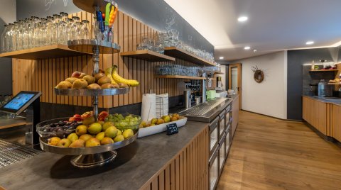 Theke mit Obstschale, Gläsern und Getränkespender in modernem Raum mit Holzboden