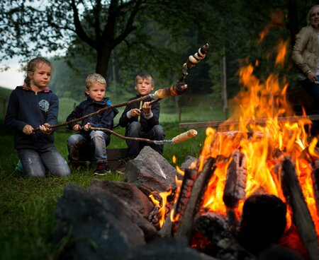 Kinder am Lagerfeuer beim Stockbrot grillen