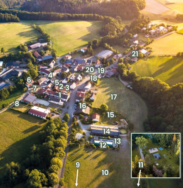 Luftaufnahme eines Dorfes mit nummerierten Gebäuden und Feldern in der Abendsonne