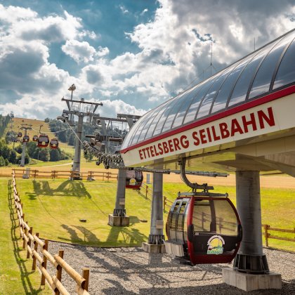 Seilbahnstation Ettelsberg Seilbahn mit Gondeln über grüner Wiese unter bewölktem Himmel
