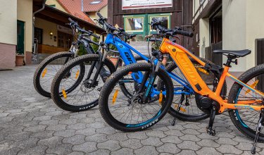 Drei bunte E-Mountainbikes nebeneinander vor einem Gebäude mit Ottonenhof-Schild