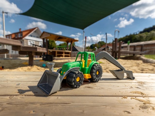 Spielzeugtraktor vor Sandkiste