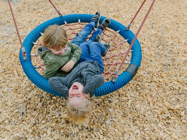 Kinder beim Schaukeln auf dem Spielplatz