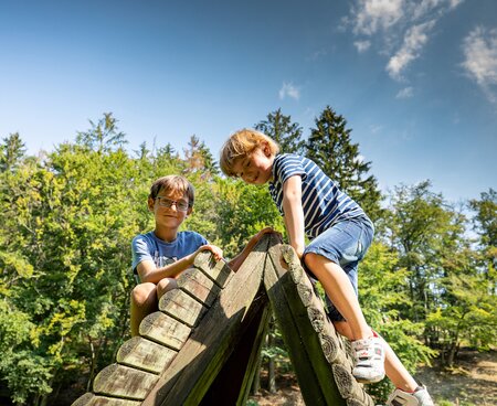 Kinder beim Klettern am Waldspielplatz