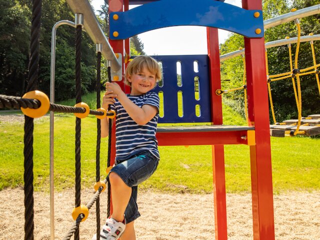 Kind beim Klettern auf dem Outdoor-Spielplatz