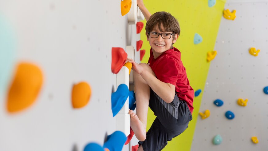 Junge beim Klettern auf der Kletterwand