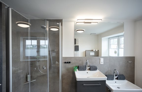 Modernes Badezimmer mit zwei Waschbecken, Spiegel und Duschkabine links