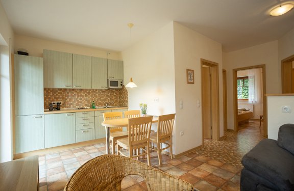 Helle Küche mit Esstisch und Stühlen, angrenzend Flur mit Türen zu weiteren Räumen