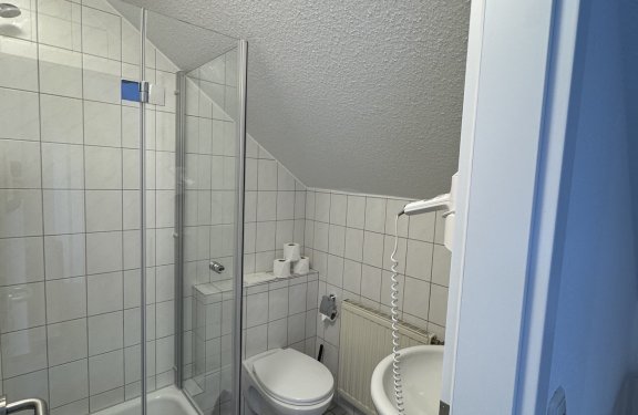 Kleines Badezimmer mit Dusche, Toilette, Waschbecken und Haartrockner an der Wand